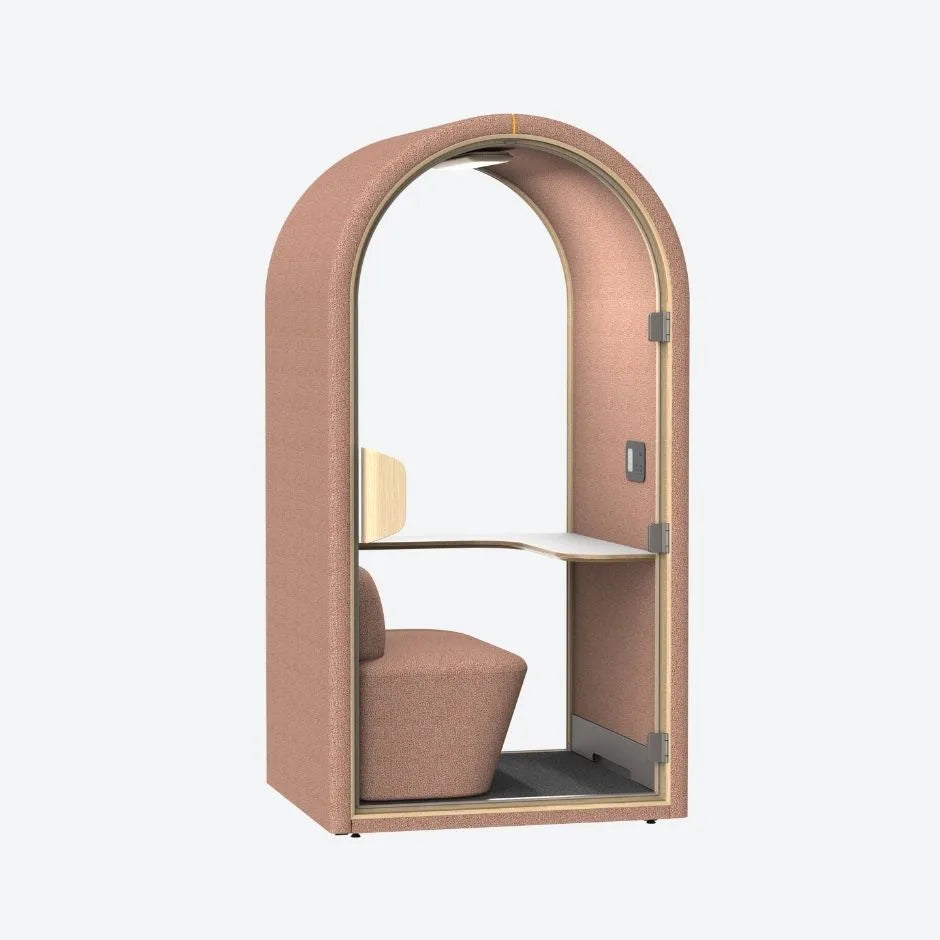 Blush pink acoustic pod with curved design, glass door, built-in desk and soft seating β ideal for quiet workspaces or private calls.