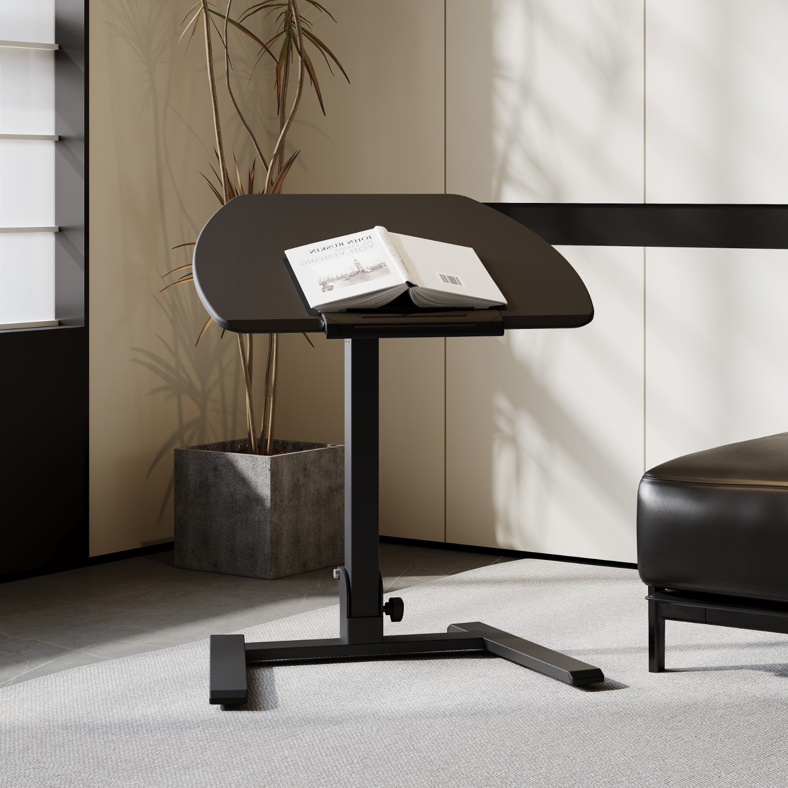 Black portable standing desk with an angled surface, shown in a modern interior with books open on top β ideal for reading or working.
