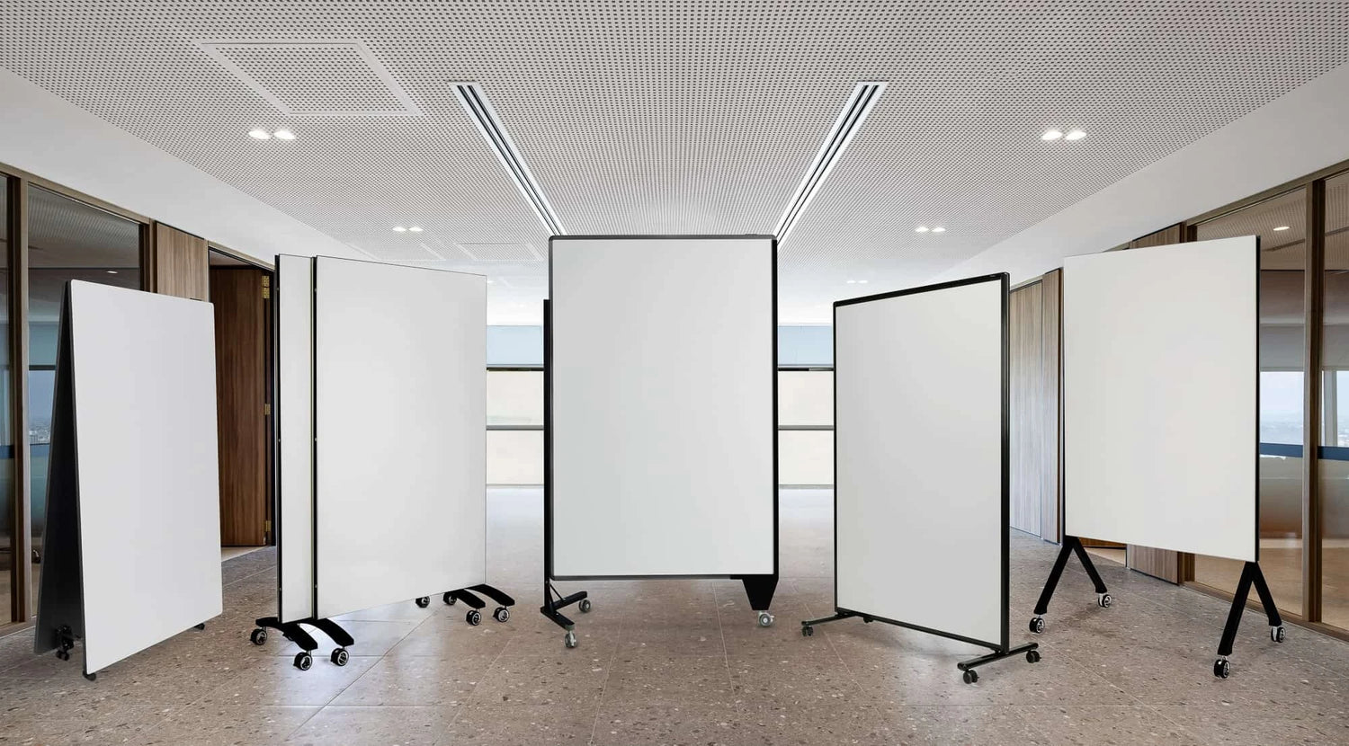 Different styles of mobile whiteboard panels displayed in a modern office space, showcasing various frame designs and caster options.