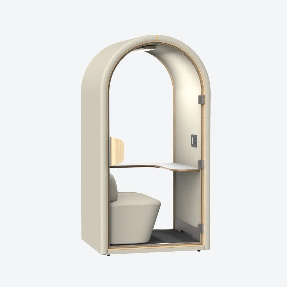 Beige acoustic pod with soft curved design, built-in seat and work desk – ideal for quiet focus in open-plan workspaces.