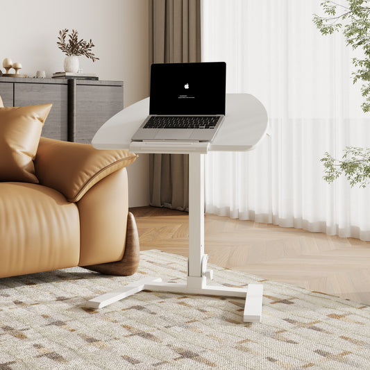 A modern white portable standing desk placed beside a leather sofa in a bright, minimalist living room, featuring a tilted laptop surface and ergonomic design.