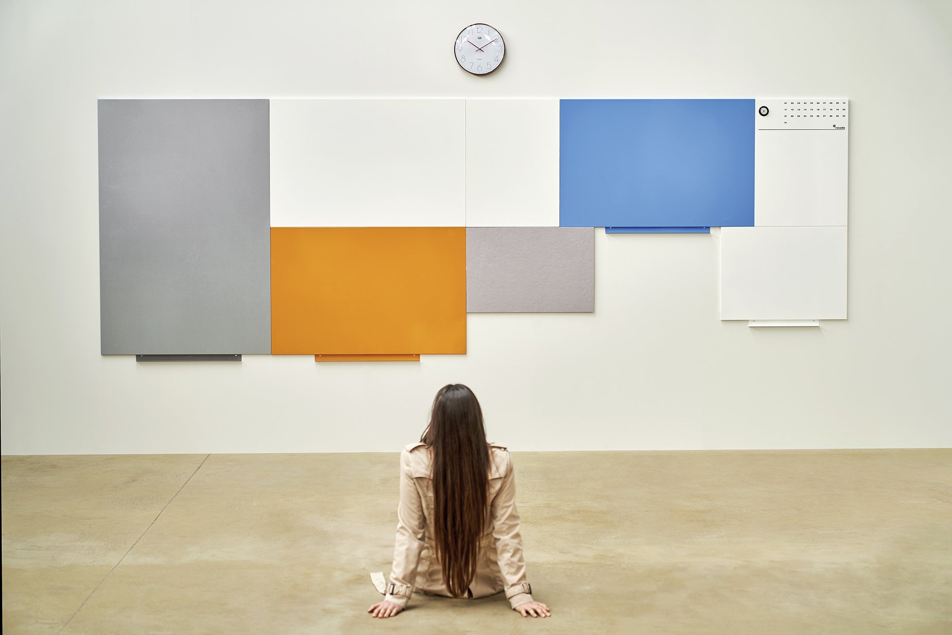 Woman sitting in front of a large modular whiteboard installation composed of colourful interconnected panels – ideal for creative planning, collaboration, and customisable workspace design.